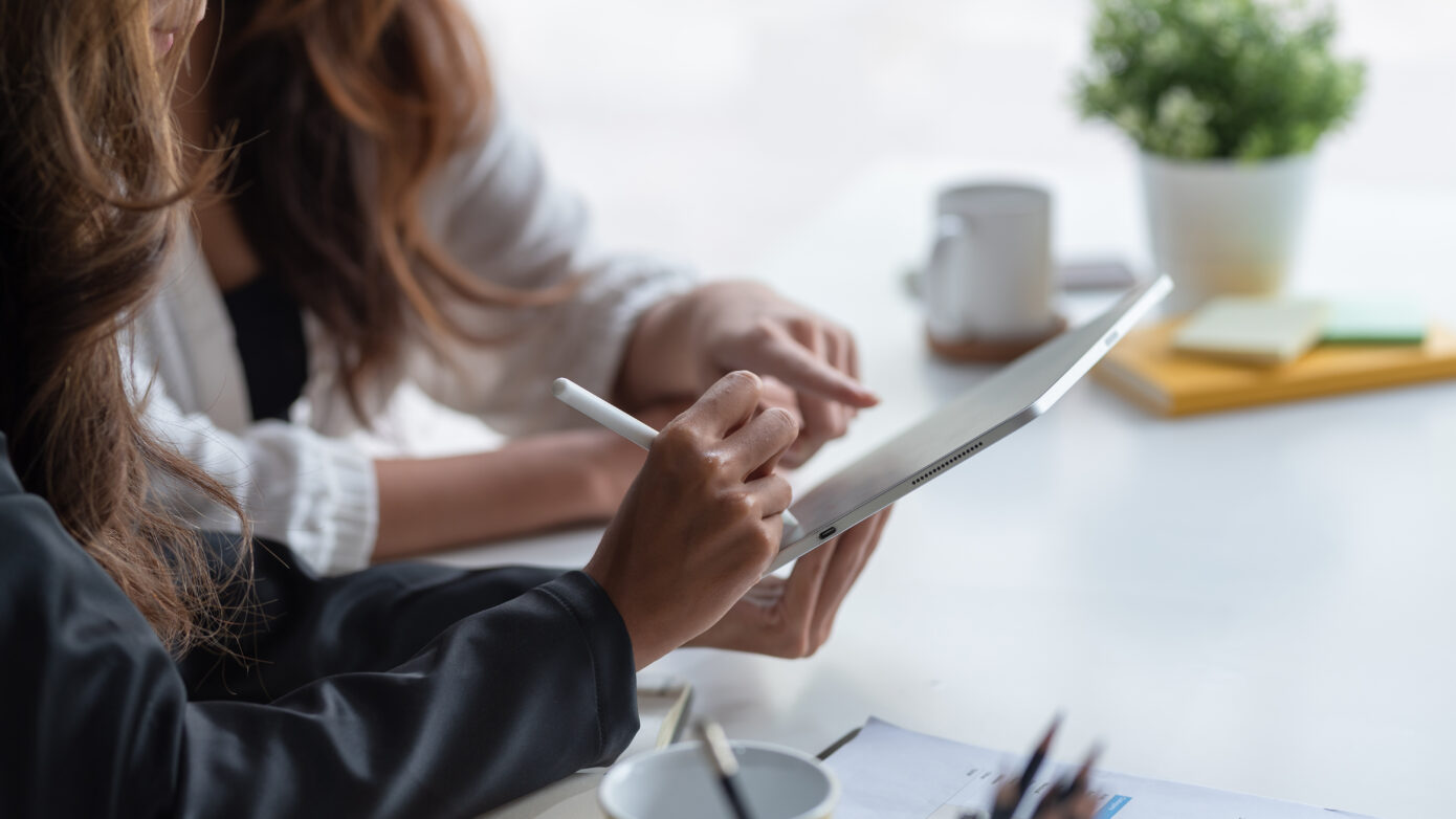 Two business woman pointing at a tablet