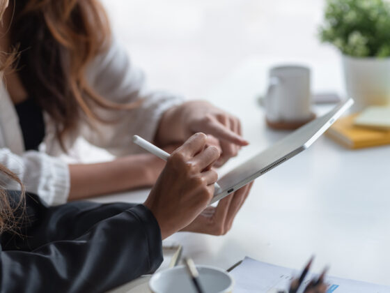 Two business woman pointing at a tablet